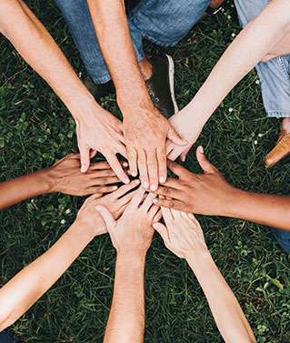 an image of a group of people with their hands in a circle to represent our company culture